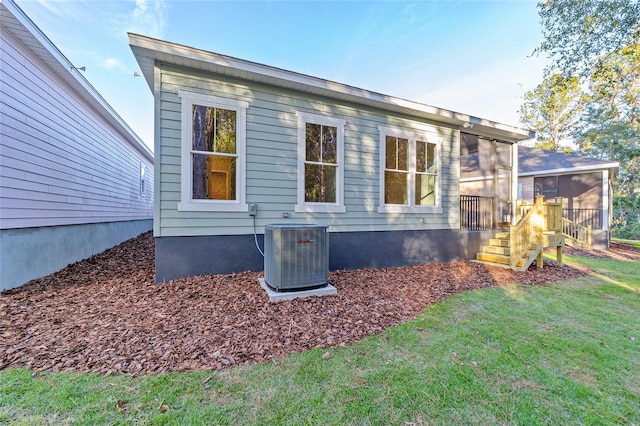 view of side of home featuring a yard, a sunroom, and central air condition unit