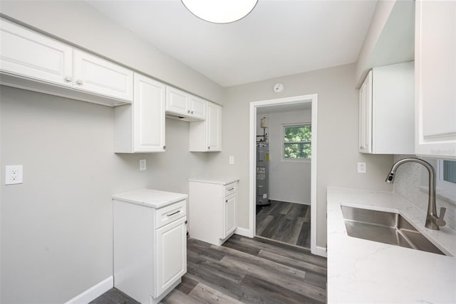 kitchen with dark hardwood / wood-style flooring, white cabinetry, sink, and water heater