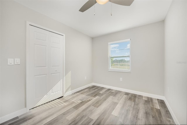 unfurnished bedroom with ceiling fan, light wood-type flooring, and a closet