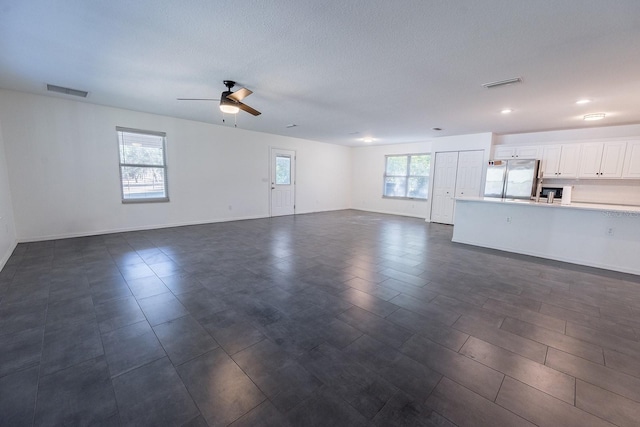 unfurnished living room featuring ceiling fan and a healthy amount of sunlight