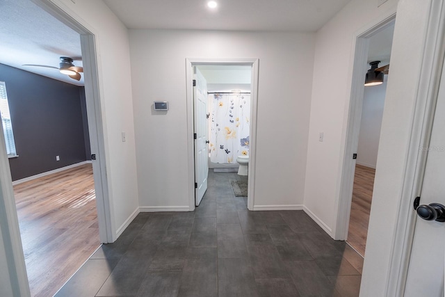 hallway with a textured ceiling and dark hardwood / wood-style floors