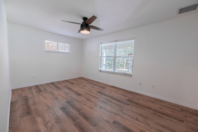 spare room featuring ceiling fan, dark hardwood / wood-style flooring, and a healthy amount of sunlight