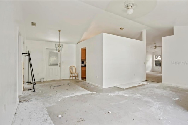 unfurnished living room with ceiling fan with notable chandelier and vaulted ceiling