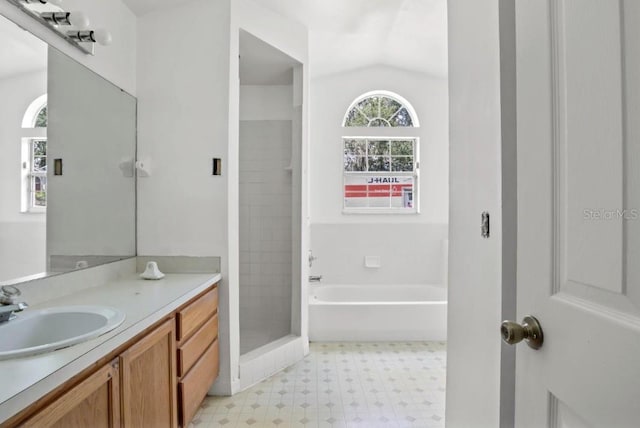 bathroom featuring vanity, independent shower and bath, and vaulted ceiling