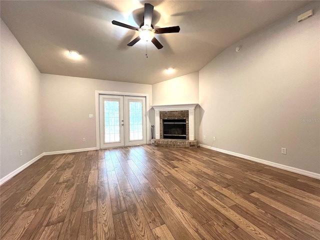 unfurnished living room featuring lofted ceiling, dark wood-type flooring, french doors, a brick fireplace, and ceiling fan