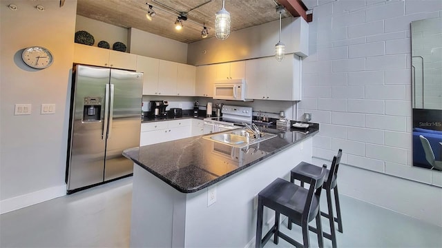 kitchen featuring white appliances, sink, decorative light fixtures, a kitchen bar, and kitchen peninsula