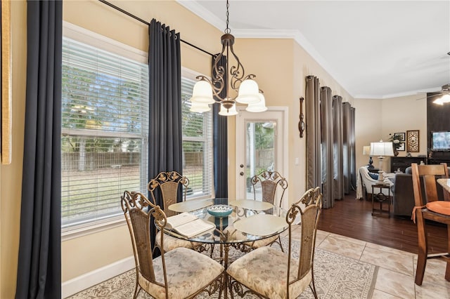 tiled dining room with ceiling fan with notable chandelier, plenty of natural light, and ornamental molding