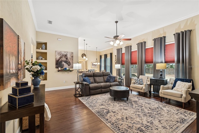 living room with built in shelves, ceiling fan, ornamental molding, and dark hardwood / wood-style floors