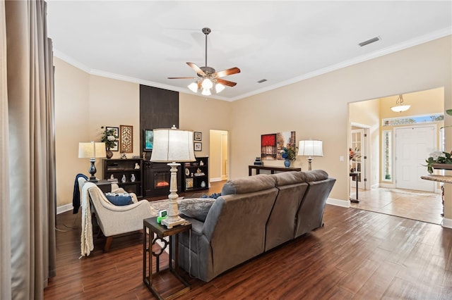 living room featuring a large fireplace, dark hardwood / wood-style floors, ceiling fan, and crown molding