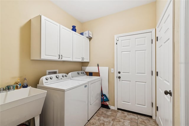 clothes washing area with cabinets, light tile patterned floors, washing machine and dryer, and sink