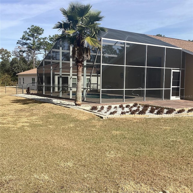 rear view of house with a lawn and a lanai