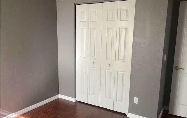 unfurnished bedroom featuring dark wood-type flooring and a closet