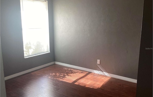 unfurnished room with a healthy amount of sunlight and dark hardwood / wood-style flooring