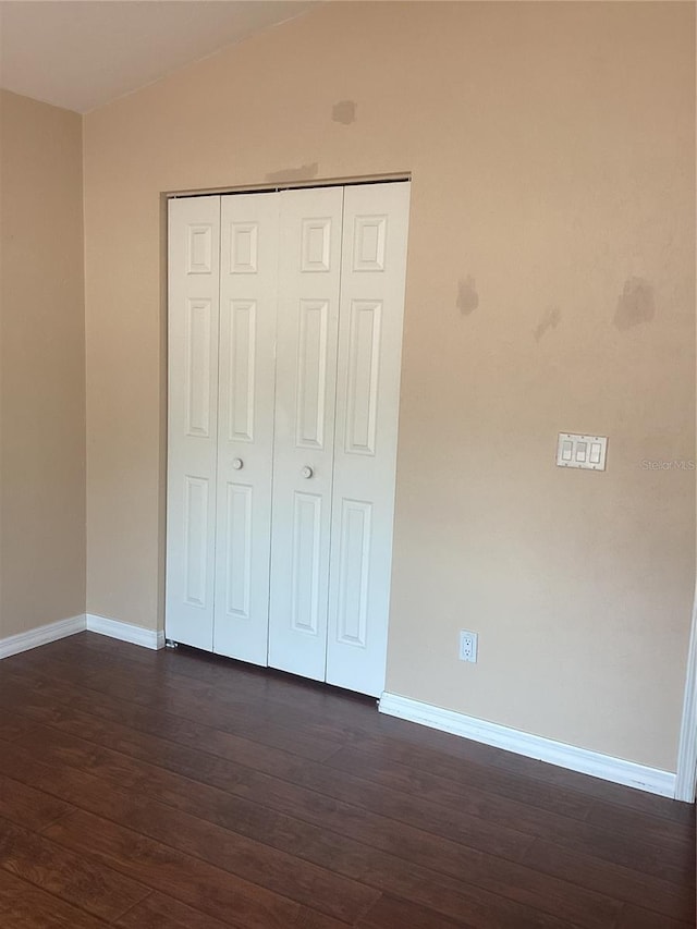 unfurnished bedroom featuring a closet and dark hardwood / wood-style flooring