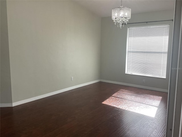 spare room featuring dark hardwood / wood-style floors, an inviting chandelier, and plenty of natural light