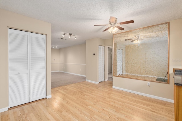 interior space with ceiling fan, a textured ceiling, and light wood-type flooring