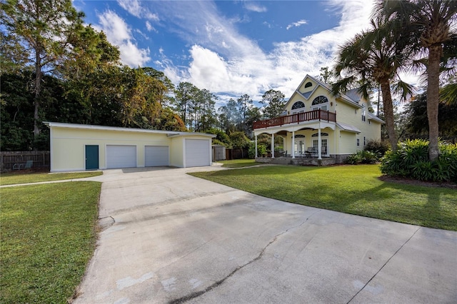 view of front of house with a balcony, an outbuilding, and a front yard