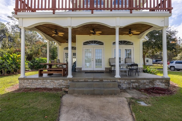 view of exterior entry with ceiling fan, french doors, and a balcony