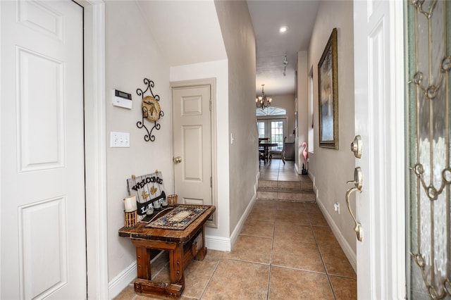 corridor with light tile patterned floors and an inviting chandelier