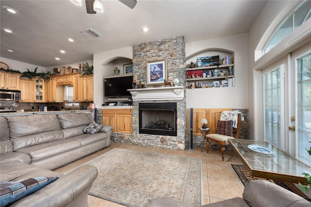 tiled living room featuring a fireplace and ceiling fan