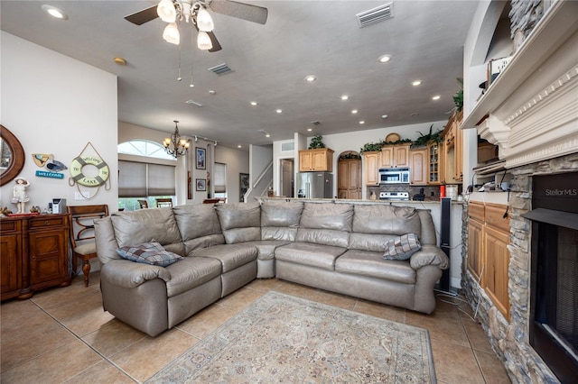 tiled living room with ceiling fan with notable chandelier