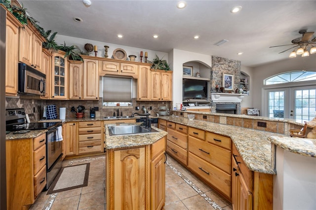 kitchen featuring kitchen peninsula, light stone counters, ceiling fan, and stainless steel appliances