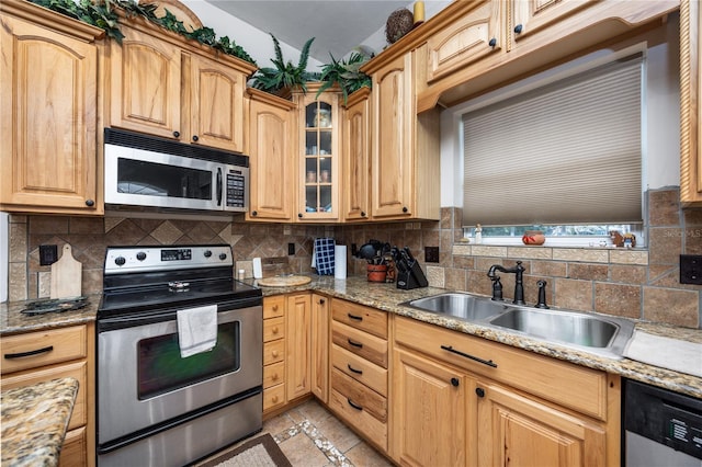 kitchen with light stone countertops, sink, backsplash, light tile patterned floors, and appliances with stainless steel finishes