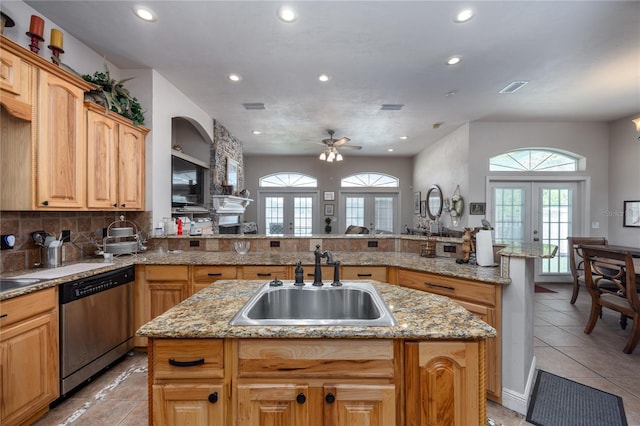 kitchen with sink, french doors, stainless steel dishwasher, kitchen peninsula, and an island with sink