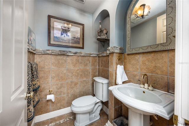 bathroom featuring toilet, tile patterned floors, tile walls, and sink