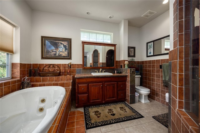 bathroom featuring vanity, tile patterned flooring, toilet, tile walls, and tiled tub