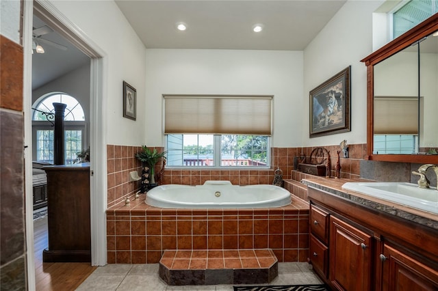 bathroom featuring tiled tub, hardwood / wood-style floors, vanity, and a healthy amount of sunlight