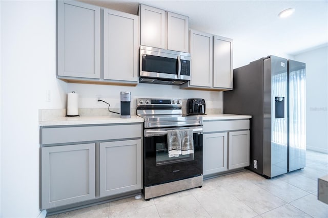 kitchen with gray cabinets, light tile patterned floors, and appliances with stainless steel finishes