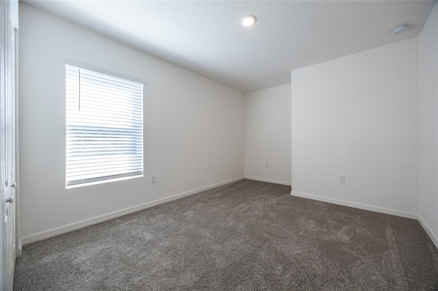 unfurnished room with dark carpet