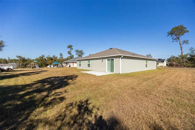 rear view of property featuring a playground, a patio area, and a yard