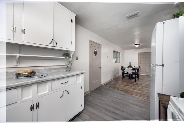 kitchen with white cabinets, white refrigerator, and light hardwood / wood-style flooring