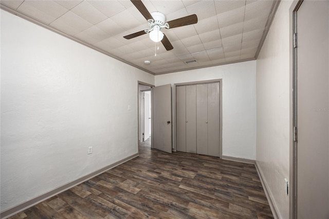 unfurnished bedroom featuring ceiling fan, a closet, crown molding, and dark wood-type flooring