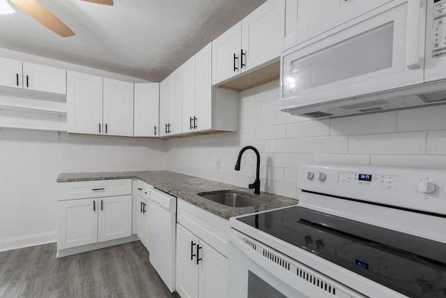 kitchen featuring stone counters, white appliances, dark wood-style flooring, a sink, and tasteful backsplash