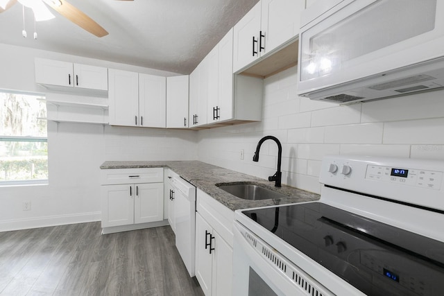 kitchen with white appliances, wood finished floors, a sink, decorative backsplash, and light stone countertops