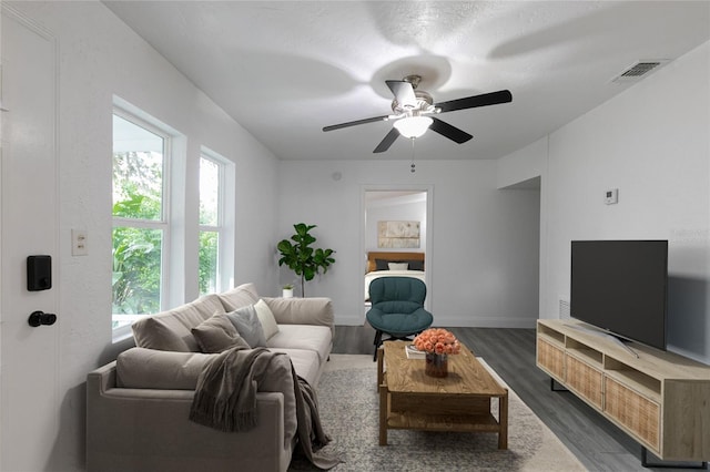 living area with a ceiling fan, visible vents, dark wood finished floors, and baseboards