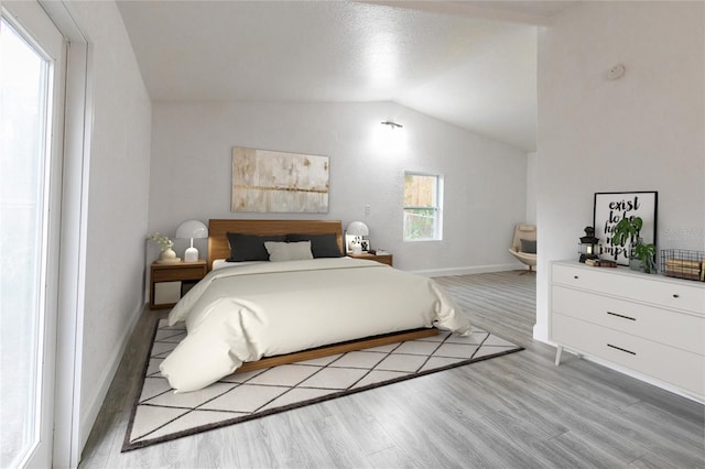 bedroom featuring lofted ceiling, wood finished floors, and baseboards