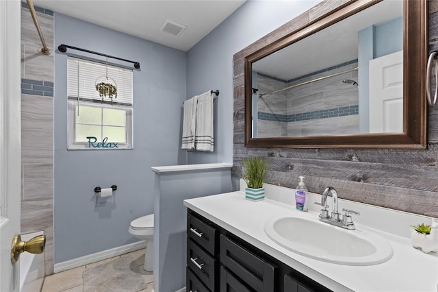 bathroom featuring tile patterned floors, vanity, toilet, and a tile shower