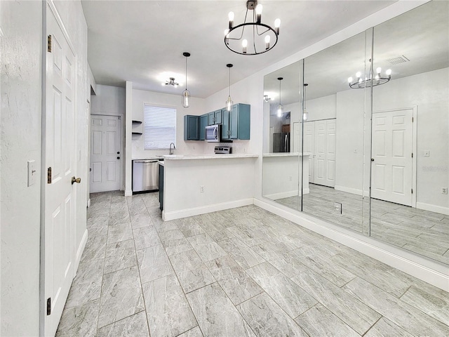 kitchen with kitchen peninsula, appliances with stainless steel finishes, a chandelier, and blue cabinets