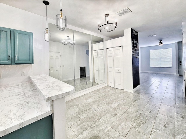 kitchen featuring ceiling fan with notable chandelier, kitchen peninsula, hanging light fixtures, and a breakfast bar