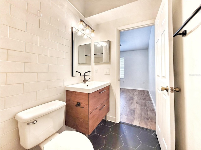 bathroom with toilet, vanity, tile walls, and hardwood / wood-style flooring