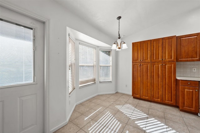 unfurnished dining area with light tile patterned floors, lofted ceiling, and a notable chandelier