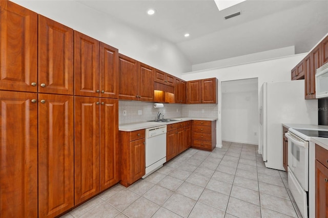 kitchen featuring tasteful backsplash, white appliances, sink, light tile patterned floors, and lofted ceiling