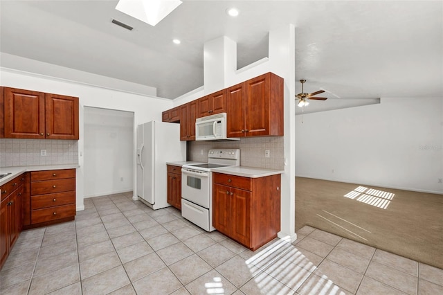 kitchen with backsplash, vaulted ceiling with skylight, white appliances, ceiling fan, and light tile patterned floors