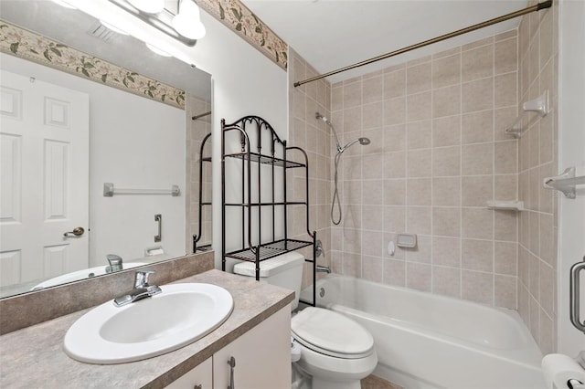 full bathroom with tiled shower / bath, vanity, and toilet