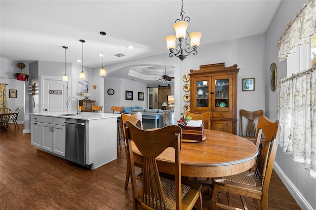 dining space with ceiling fan with notable chandelier, dark hardwood / wood-style floors, and sink