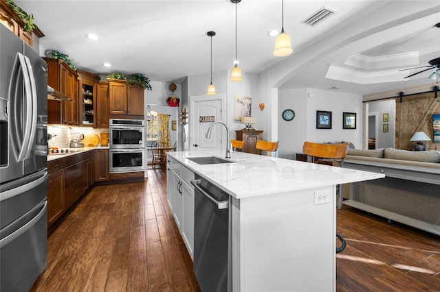 kitchen featuring appliances with stainless steel finishes, a kitchen breakfast bar, ornamental molding, sink, and a barn door